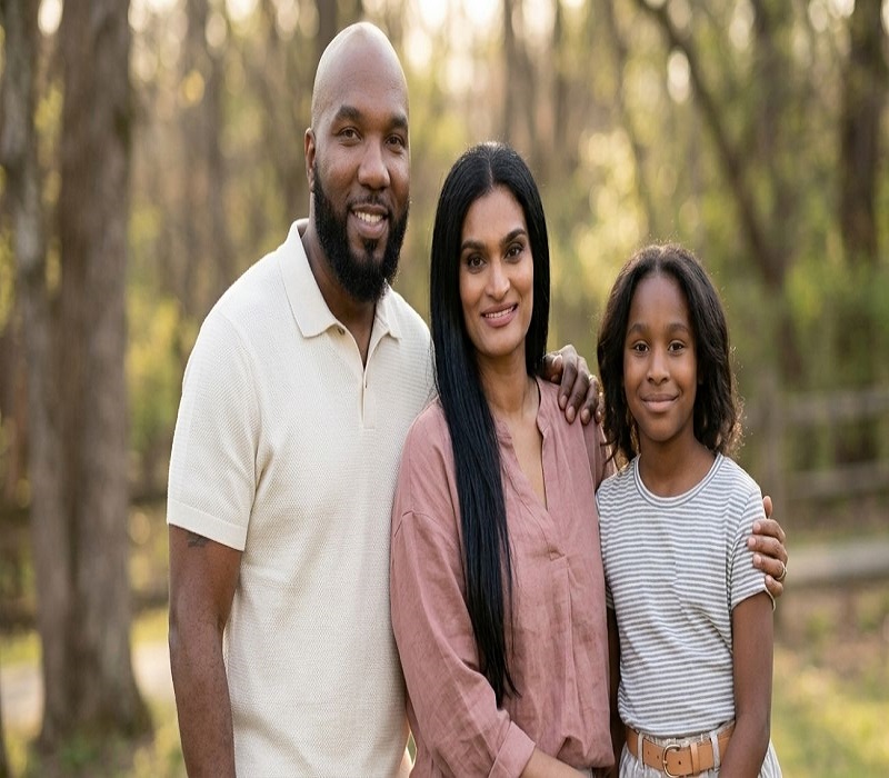 Amra Nor Jenkins with her father Young Jeezy and mother Mahlet Mahi Gebremedhin posing together for a family photo outdoors surrounded by trees.